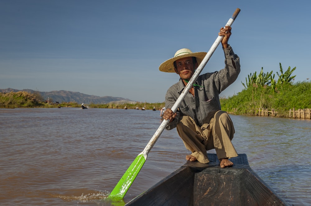 a man in a straw hat is rowing a boat