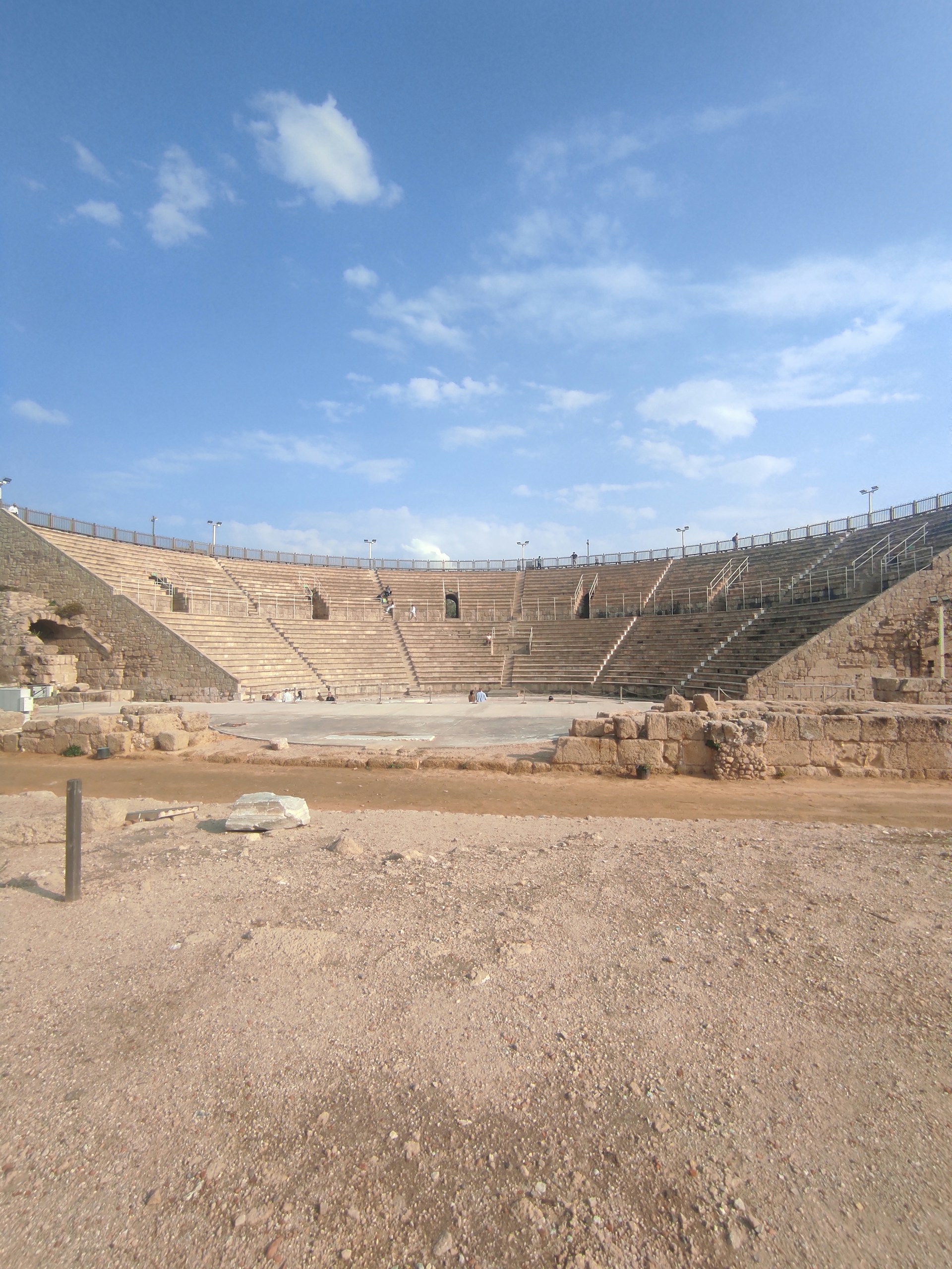 a dirt field next to a large stone structure