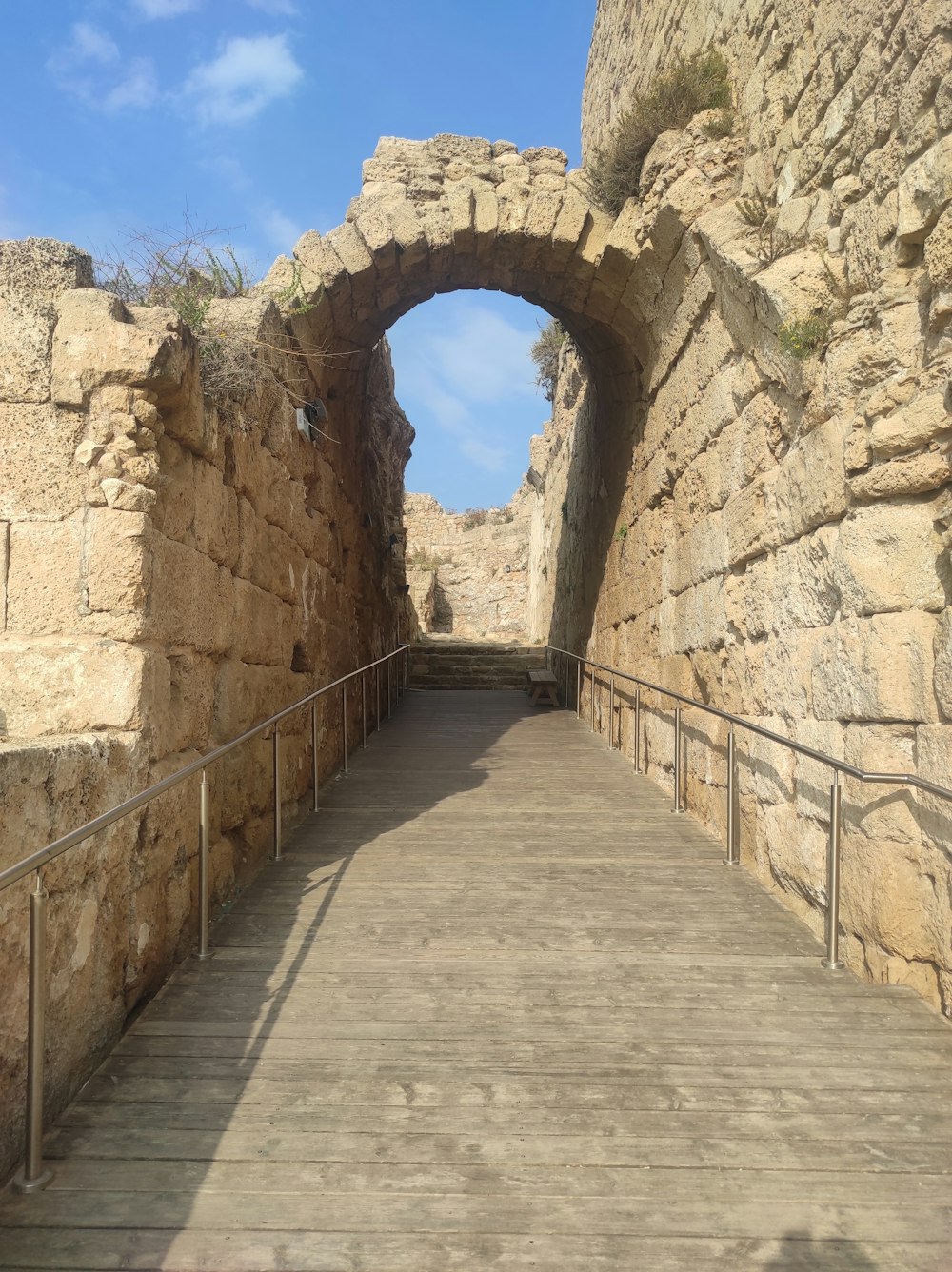 石のトンネルを抜ける木製の歩道