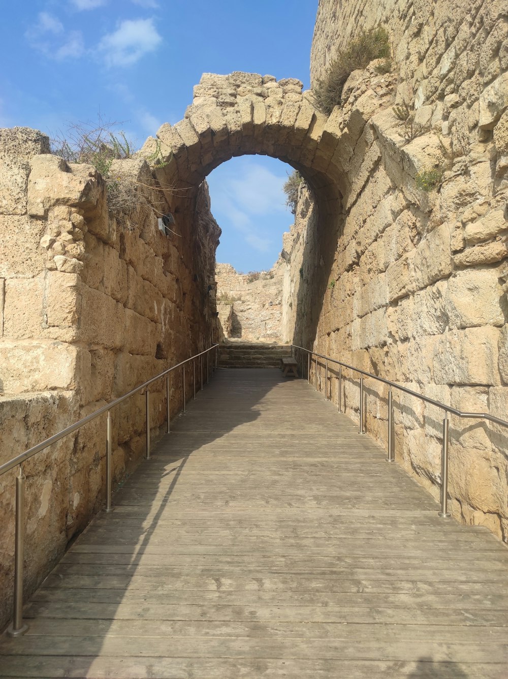 una pasarela de madera que atraviesa un túnel de piedra