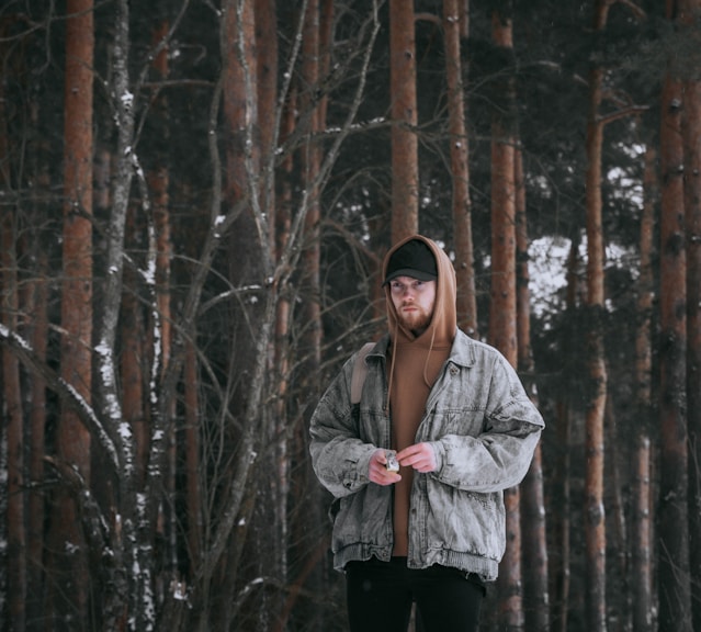 a man standing in the snow in front of a forest
