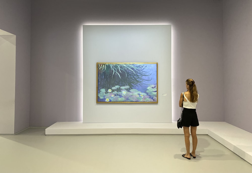 a woman looking at a painting in a museum