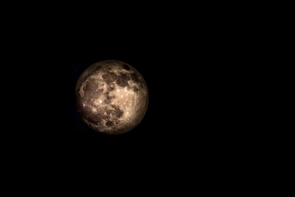 a full moon is seen in the dark sky