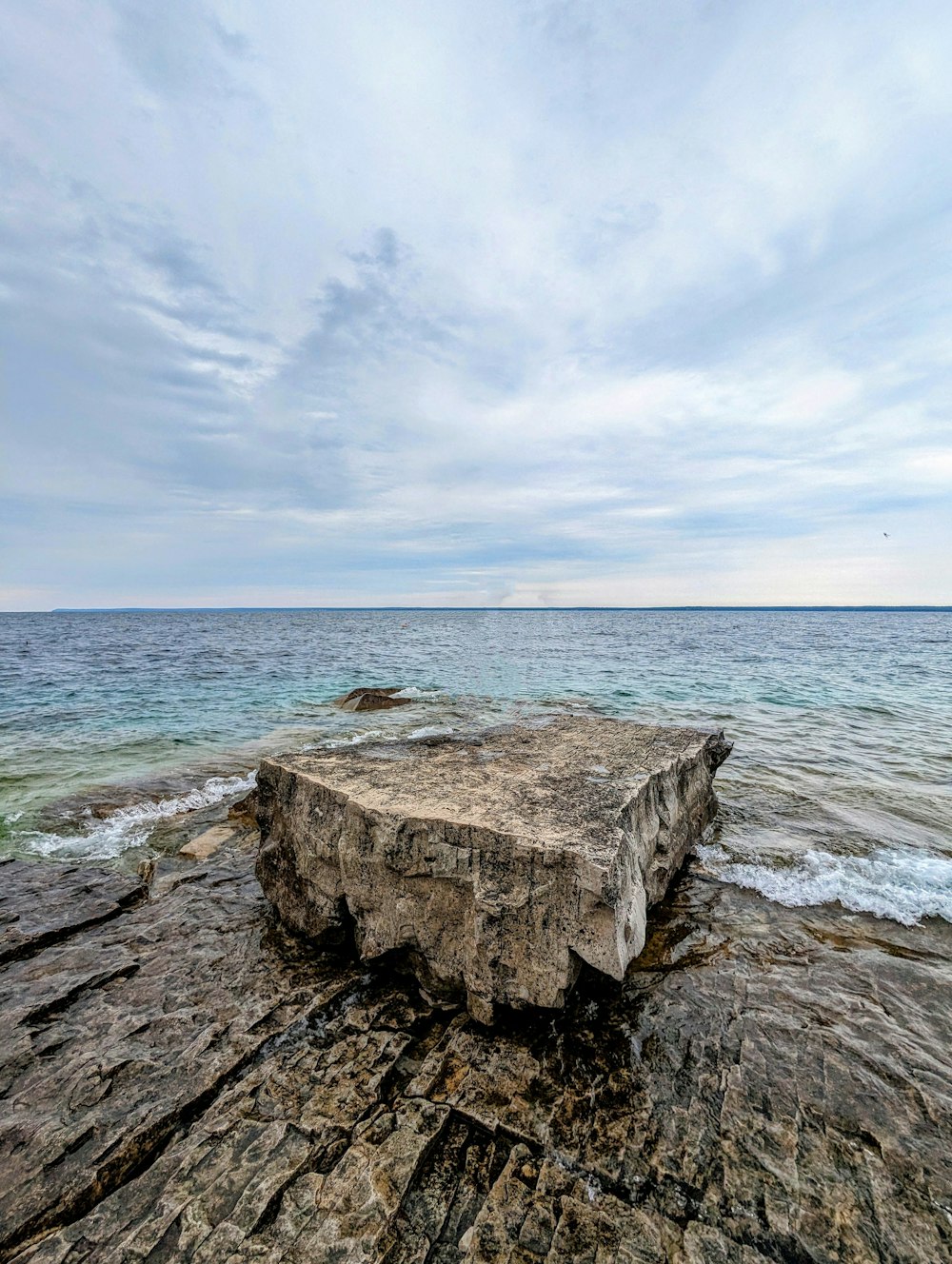 a large rock sitting on top of a beach next to the ocean