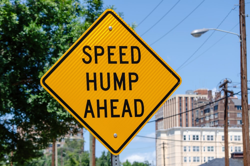 a yellow speed hump sign sitting on the side of a road