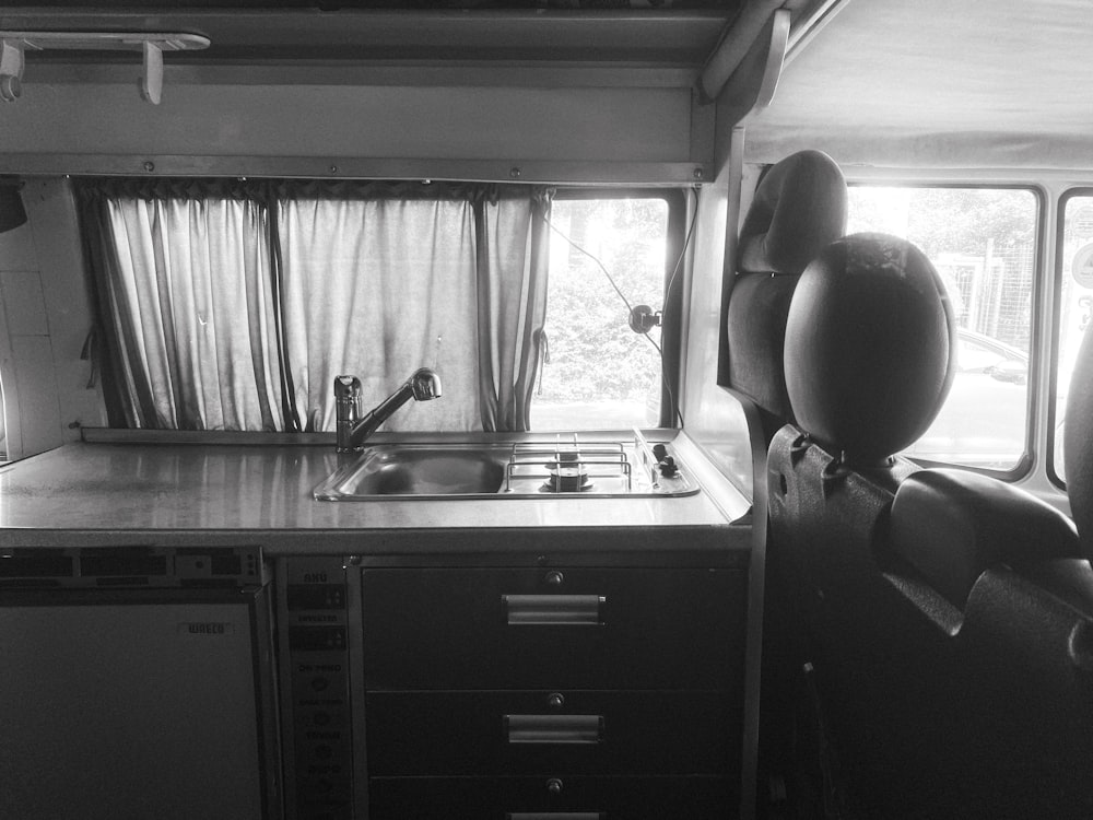 a black and white photo of a kitchen in a bus