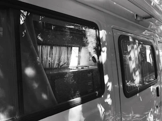Black and white photo of a custom van interior with wooden cabinetry, highlighting clean lines and modern design.