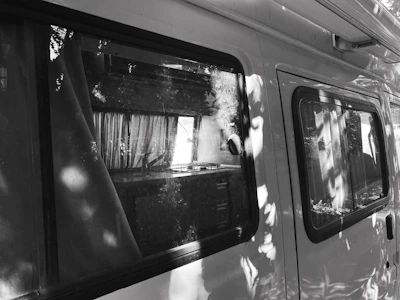 Black and white photo of a custom van interior with wooden cabinetry, highlighting clean lines and modern design.