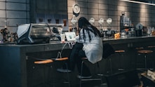 a woman sitting at a bar with a laptop