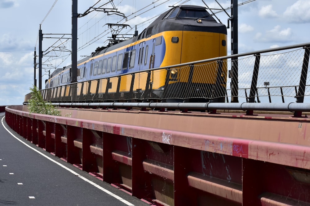 a yellow and blue train traveling over a bridge