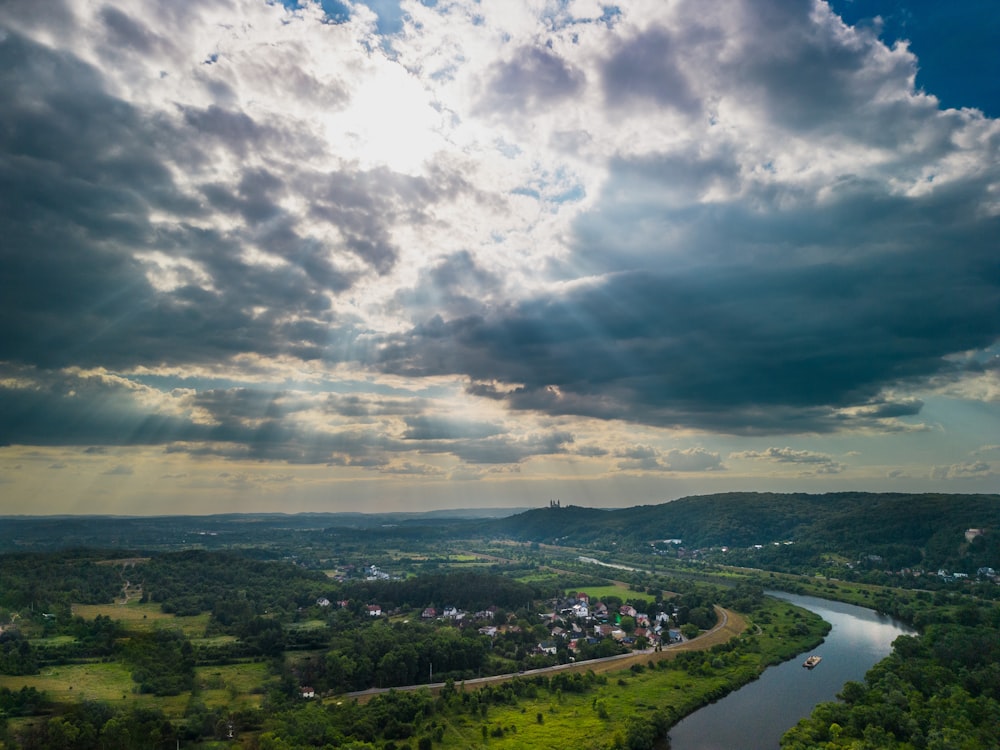 a river running through a lush green countryside under a cloudy sky