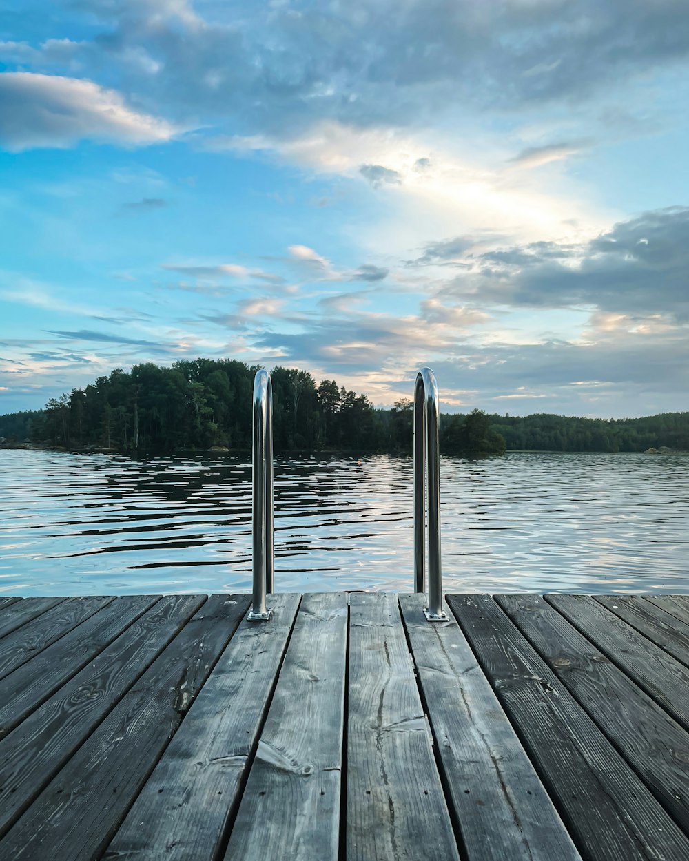 a wooden dock with two metal poles sticking out of the water