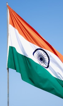 A vibrant Indian tricolor flag fluttering against a clear blue sky.