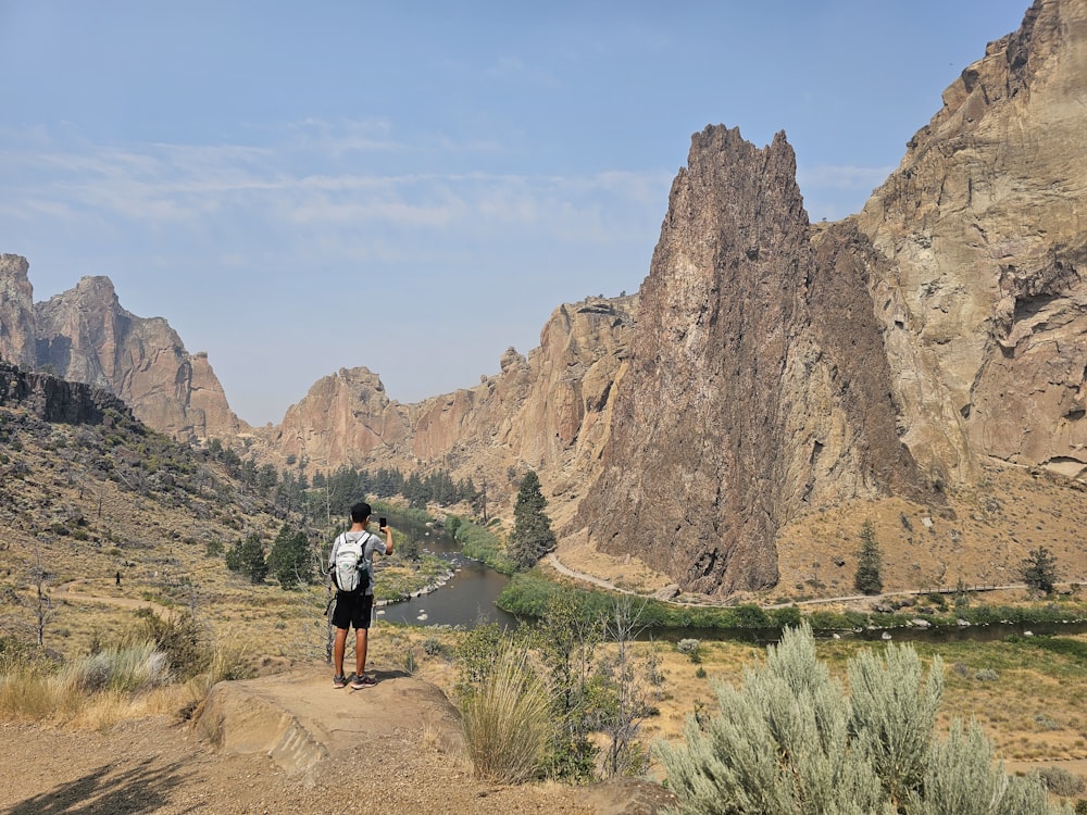 a man standing on a dirt road in front of mountains