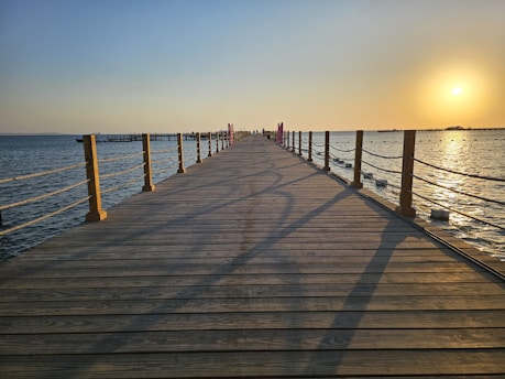 a long wooden pier stretching out into the ocean
