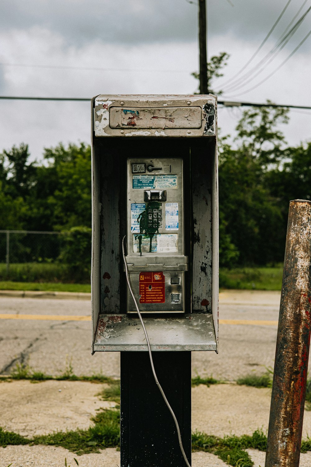 an old pay phone sitting on the side of the road