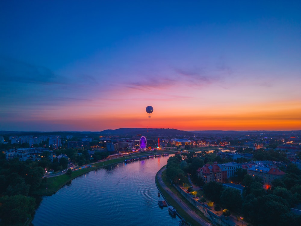 a hot air balloon flying over a river at sunset