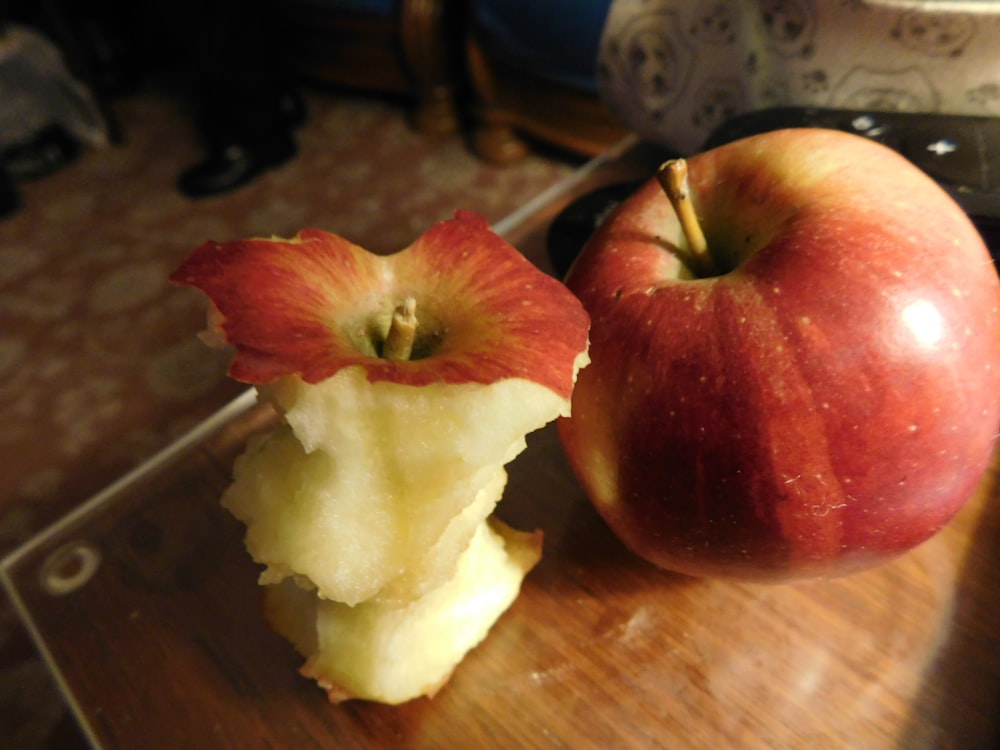 a red apple sitting on top of a wooden cutting board