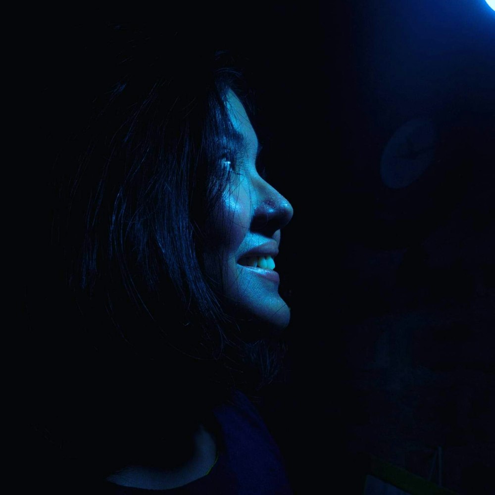 a woman in a dark room with a blue light
