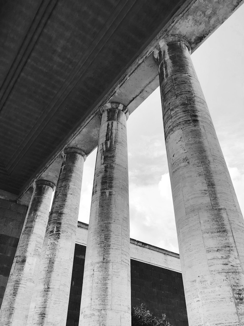 a black and white photo of pillars under a bridge