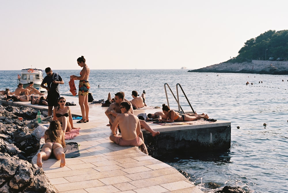 a group of people sitting on a pier next to a body of water