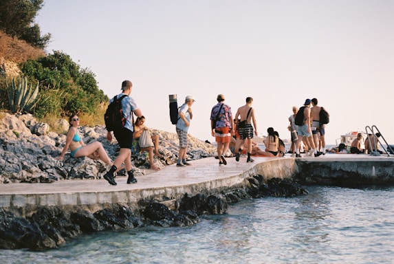 a group of people standing on a pier next to a body of water