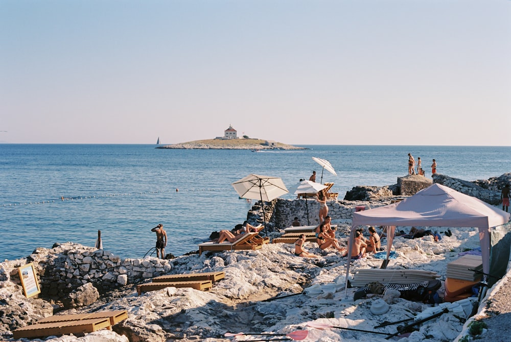 a group of people sitting on a rocky beach next to the ocean