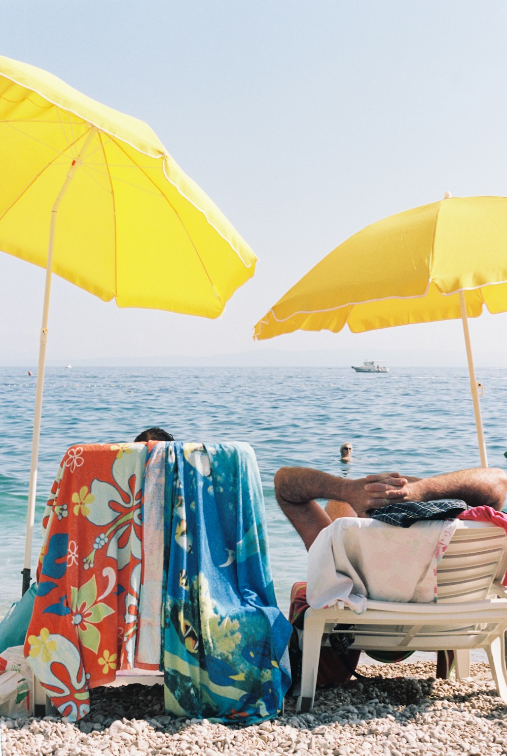 a man laying on top of a beach under yellow umbrellas