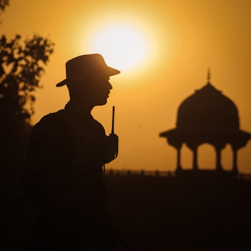 a silhouette of a man holding a stick in front of a sunset