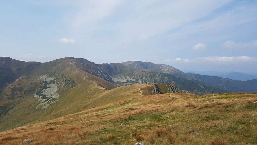 a grassy hill with mountains in the background