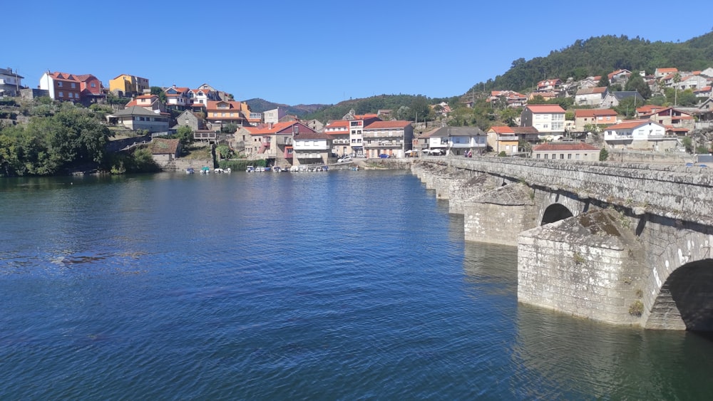 a bridge over a body of water with houses in the background