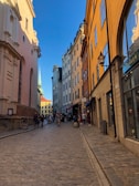 Smiling tourists exploring the colorful streets of a European city with historic buildings.
