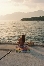 a woman is sitting on the edge of the water