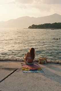 a woman is sitting on the edge of the water