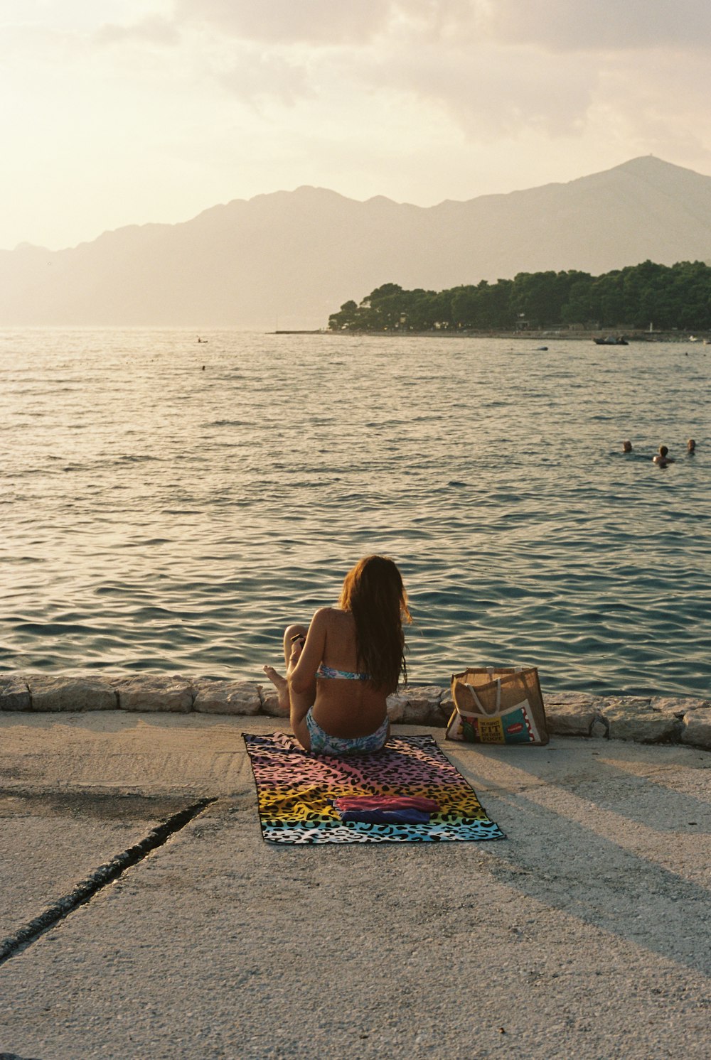 a woman is sitting on the edge of the water