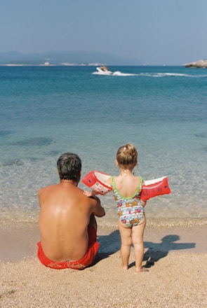 a man and a child sitting on the beach