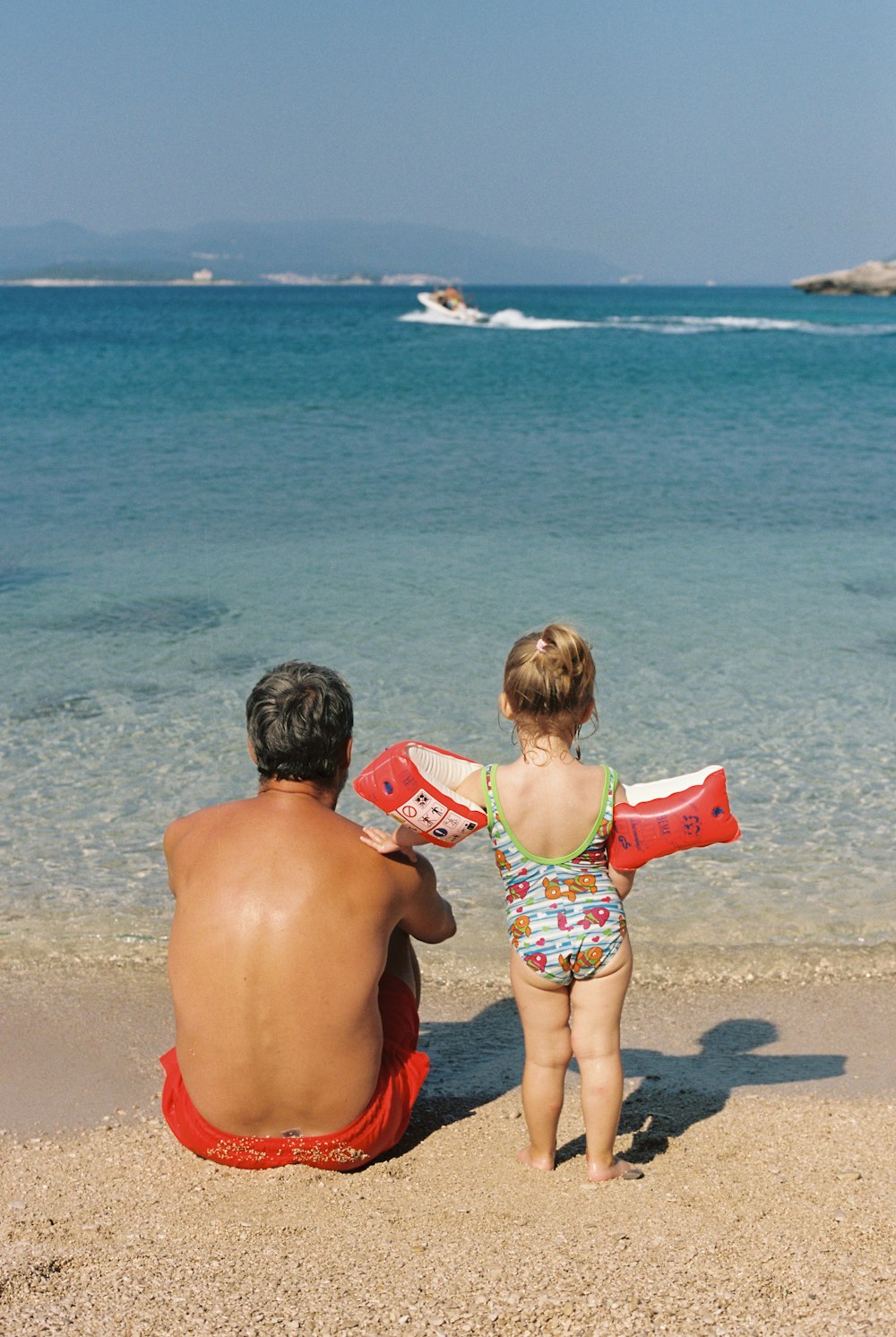 a man and a child sitting on the beach