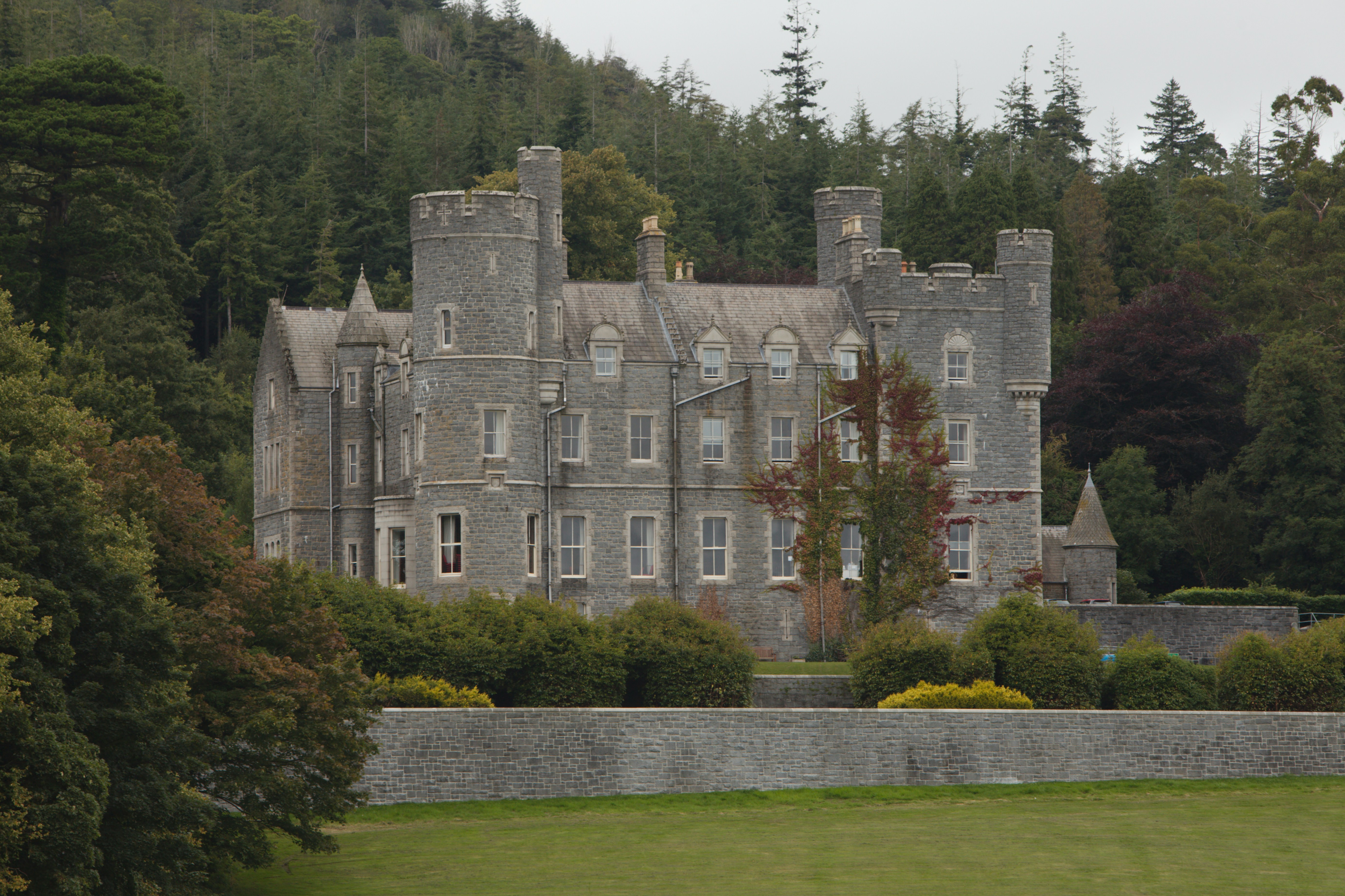 a large castle like building sitting on top of a lush green hillside
