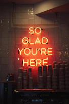 a neon sign that says so glad you're here
