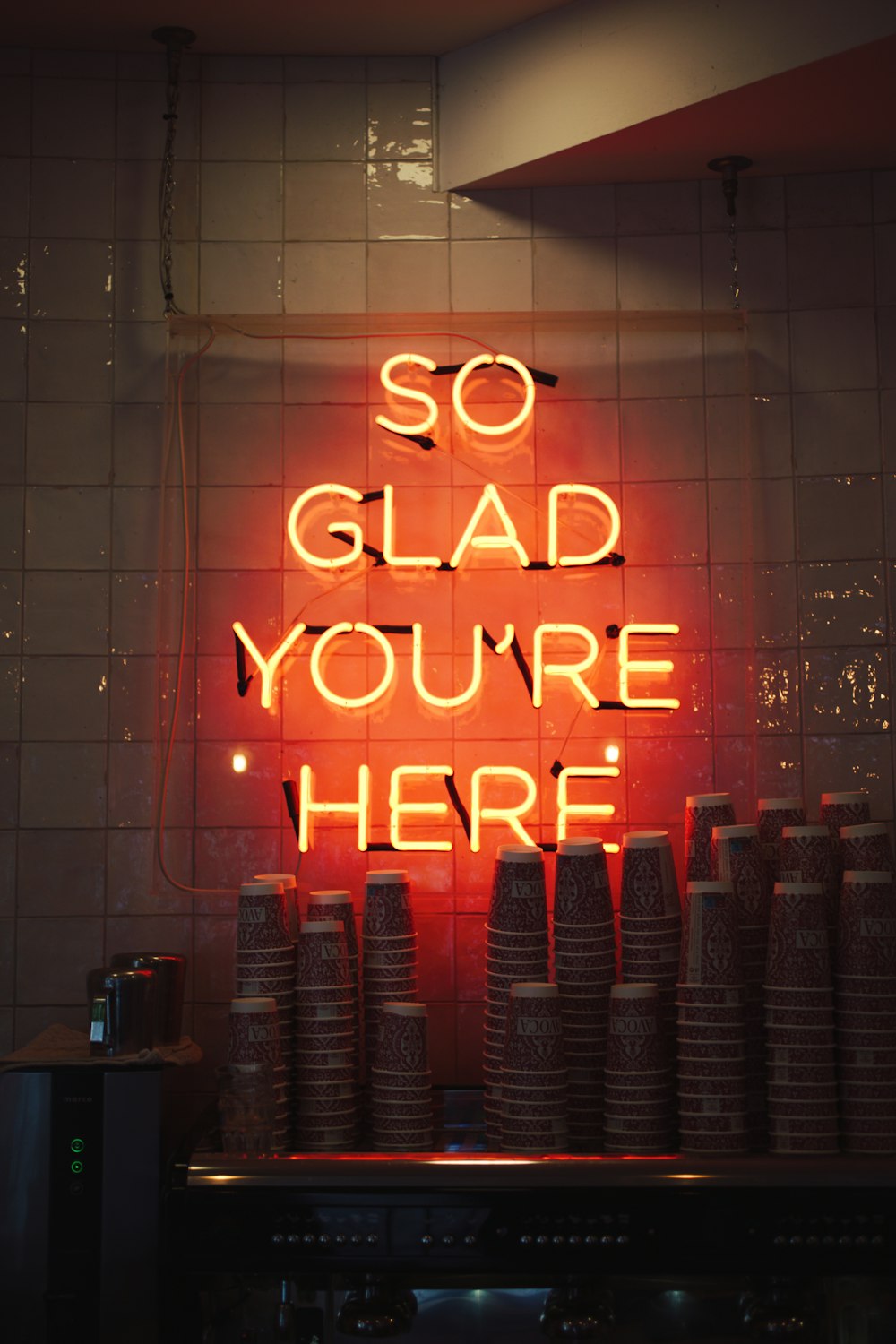 a neon sign that says so glad you're here