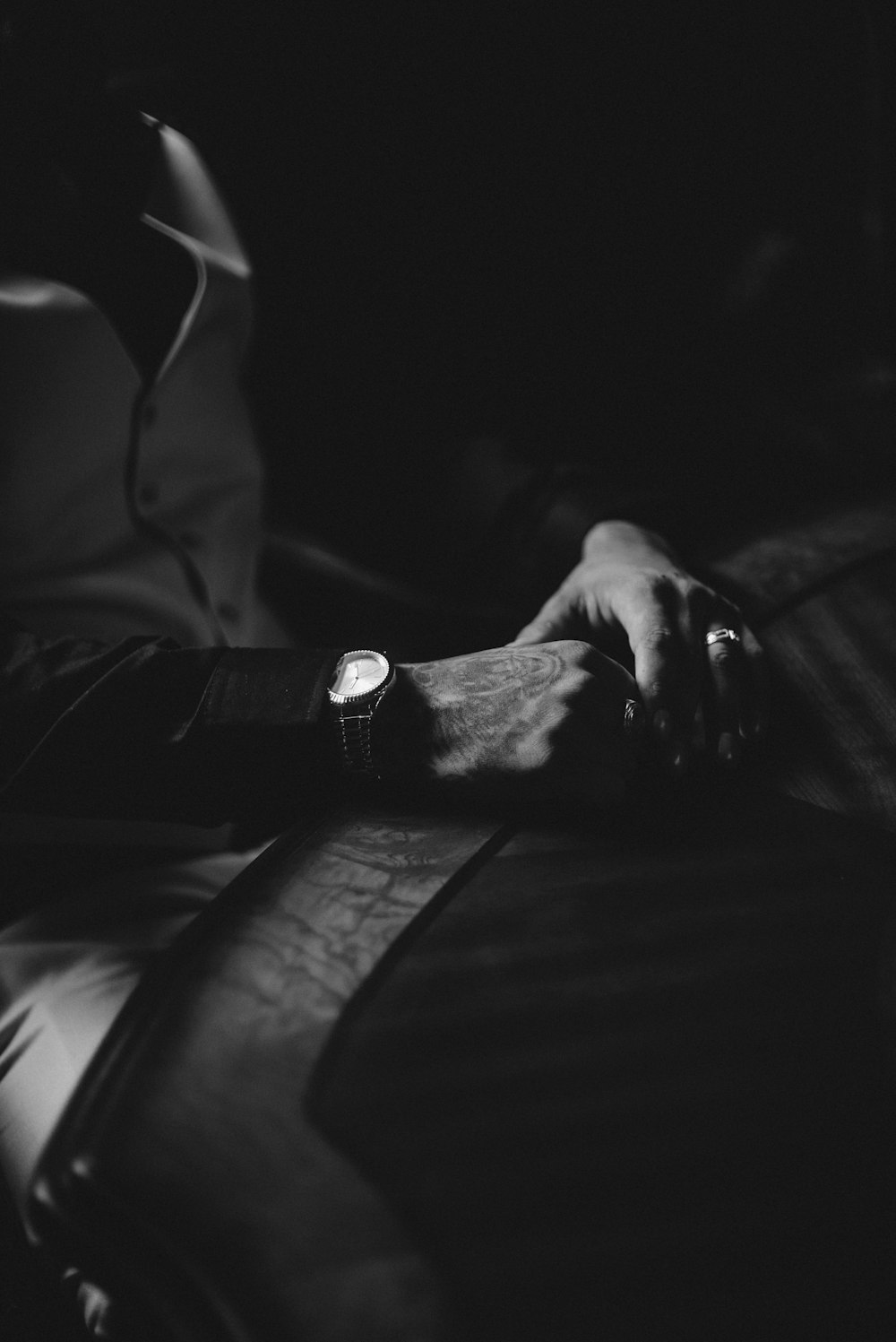 a black and white photo of a person's hand resting on a chair