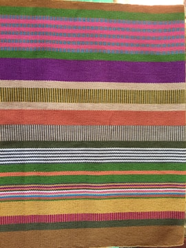 Brightly colored striped hair bow handmade with textured fabric.