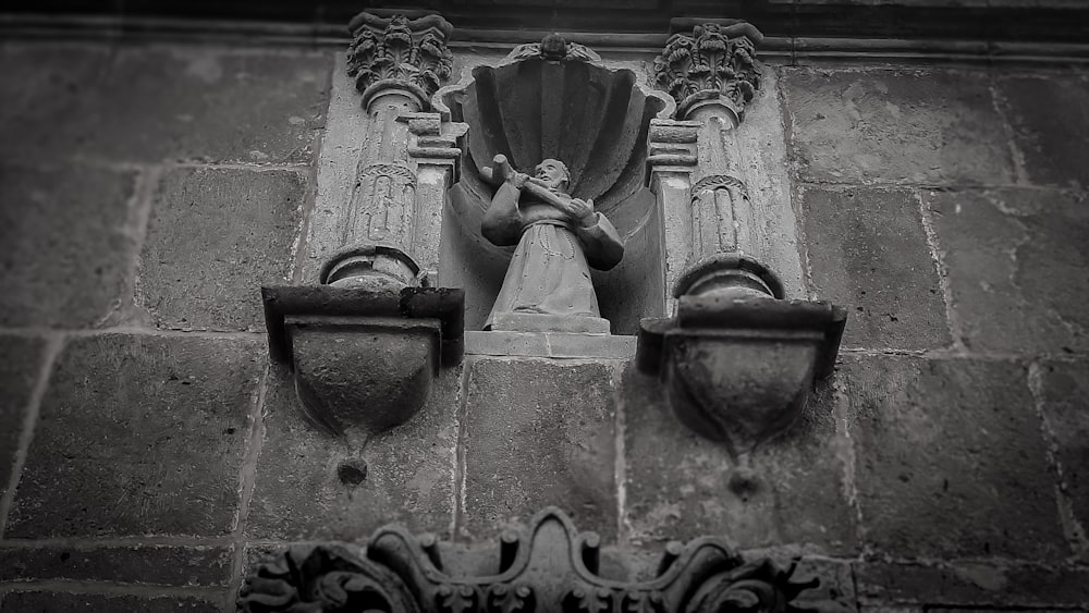 Ein Schwarz-Weiß-Foto einer Statue an der Seite eines Gebäudes