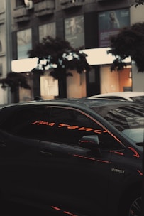 A sleek green and black hybrid car parked in front of a Las Vegas cityscape at dusk.