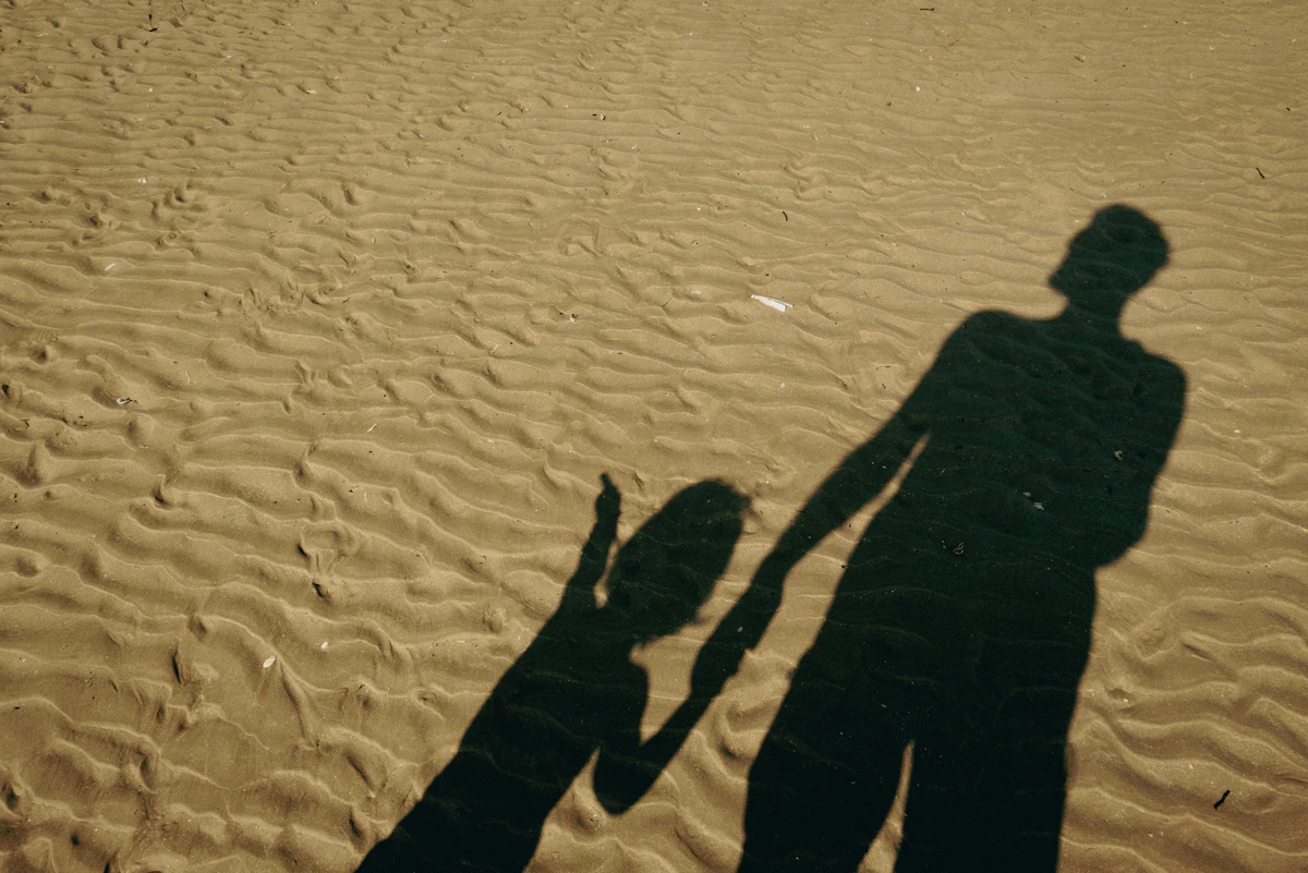 Bayangan seorang pria dan anak di pantai