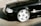 A black luxury sedan is parked, showcasing a shiny, polished chrome wheel with a five-spoke design. The vehicle's exterior is clean and reflects light, indicating a well-maintained condition.
