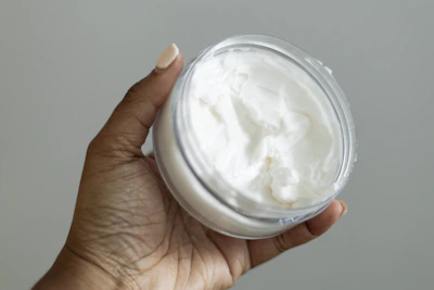 a hand holding a jar of whipped cream