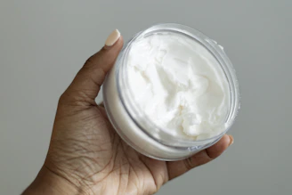 a hand holding a jar of whipped cream