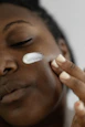 Close-up of a hand applying creamy lotion with a soft glow on the skin.
