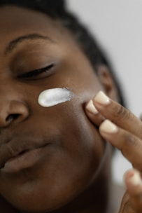 A close-up of a hand applying a creamy moisturizer onto a smooth skin surface.